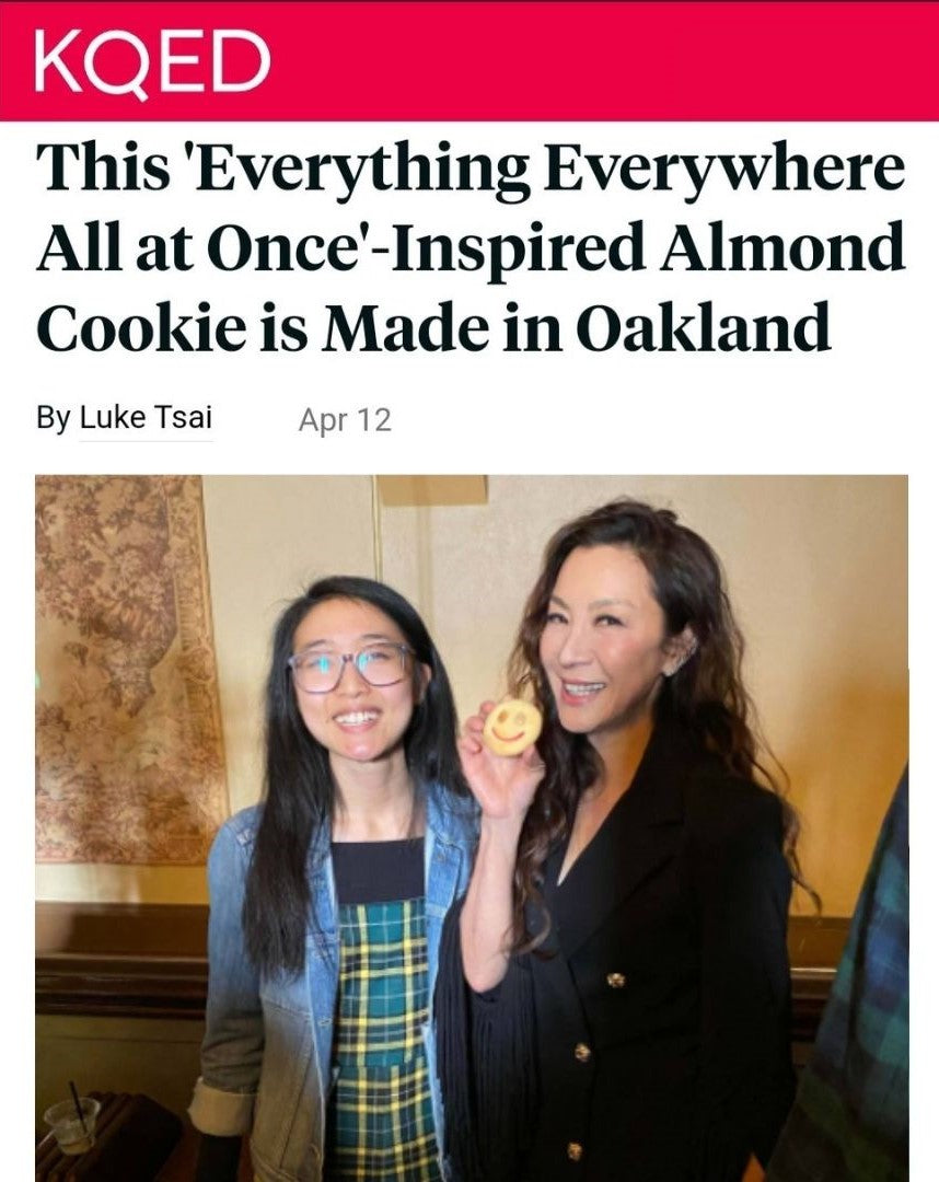 Annie Wang alongside Michelle Yeoh at the premiere of Everything Everywhere All At Once in San Francisco's Castro Theater. Michelle Yeoh holding Annie's T Cakes custom smile almond cookie. Both smiling at the camera.