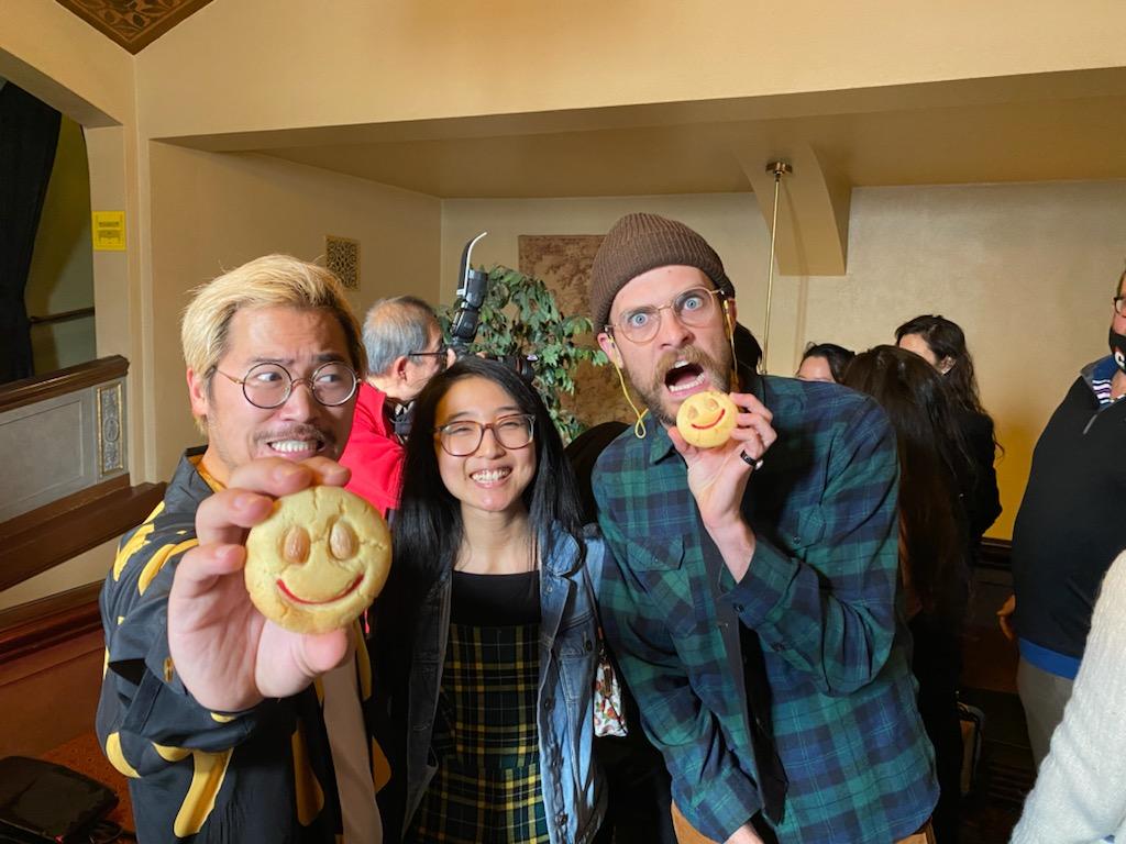 Daniel Kwan and Daniel Scheinert, directors of Everything Everywhere All At Once holding up the smiley almond cookies made by Annie's T Cakes. Picture was taken at the Castro Theater for the premier of Everything Everywhere All At Once.